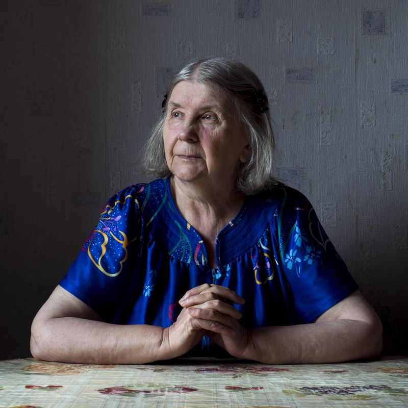 © Maria Quigley - Babushka sits at the kitchen table and looks out the balcony window.
