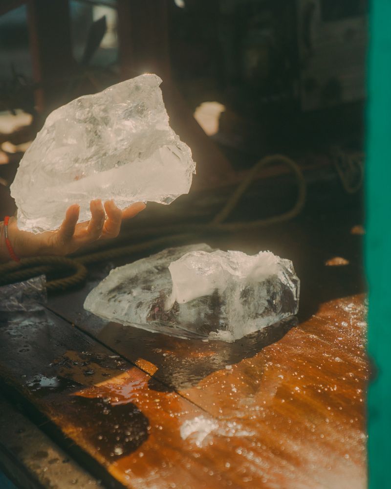 © Calvin Chow - [Untitled(Ice)] An ice seller splits a block of ice in Kampong Luong floating village, Tonle Sap lake, Cambodia.