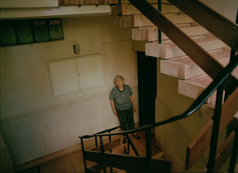 © Dana Golan - Avigail standing at her apartment entrance studying the architecture of her home of 26 years.