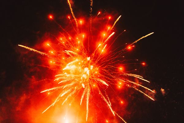 © Ryley Clarke - Bright orange and yellow fireworks exploding against a dark night sky, with trails of sparks radiating outward.