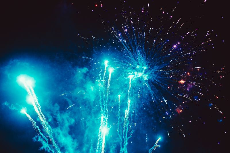 © Ryley Clarke - Bright blue fireworks exploding in the night sky with streaks and sparkles.