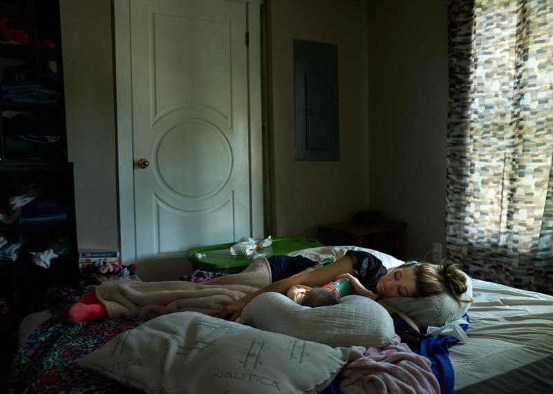 © Stacy Kranitz - Mayron has a headache and falls asleep next to her daughter, Elayna.