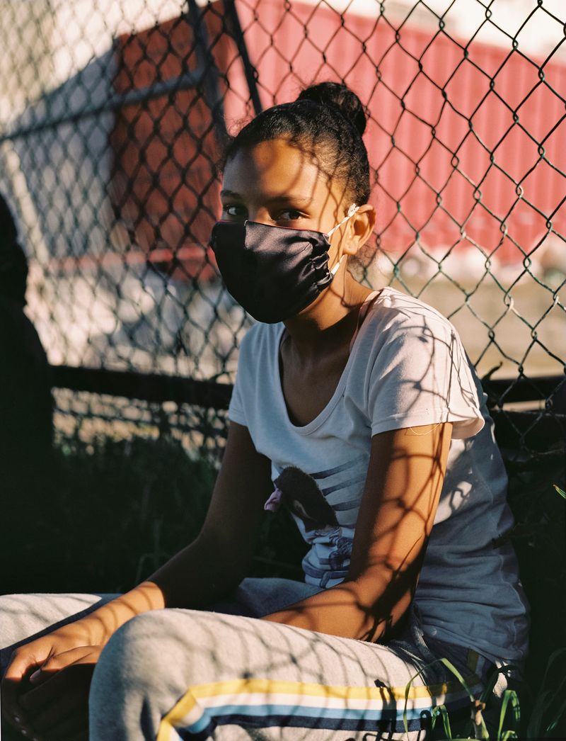 © Ayesha Kazim - A young girl wears her face mask while waiting to receive lunch from the Bo Kaap Cultural Hub.