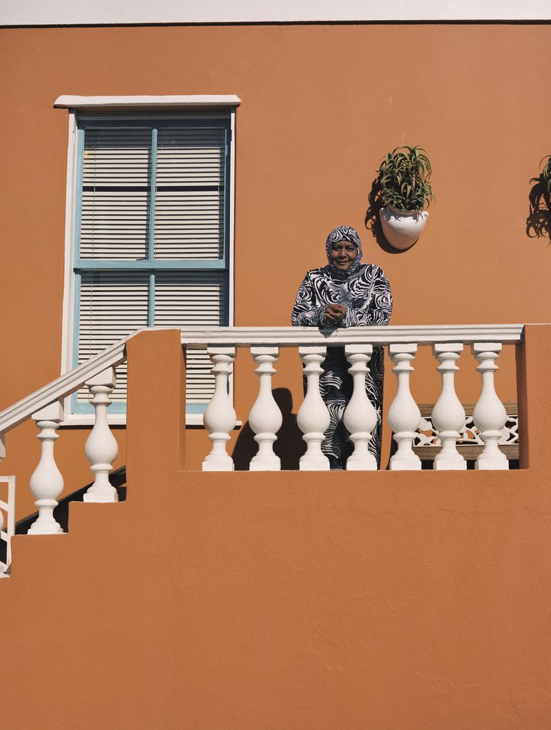 © Ayesha Kazim - Rashieda, a long-time resident of Bo Kaap, stands for a portrait from her balcony on Wale Street.