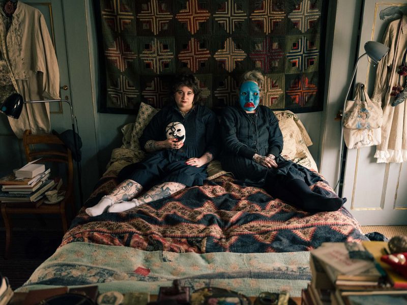 © Fotómetro - Lois and her mother Carey wearing their home-made clay masks, while also wearing the same dress, lying on Carey's bed.