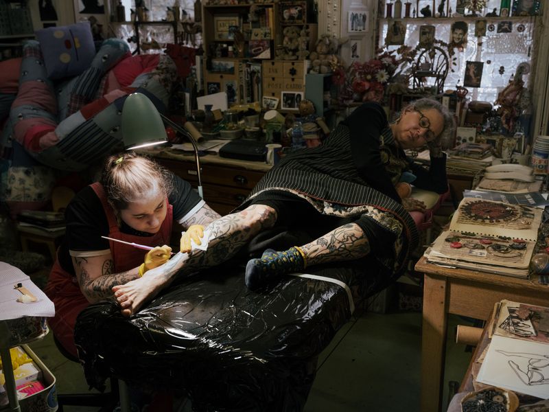 © Fotómetro - Lois tattooing her mother Carey, in her home studio, using a hand-poke technique.