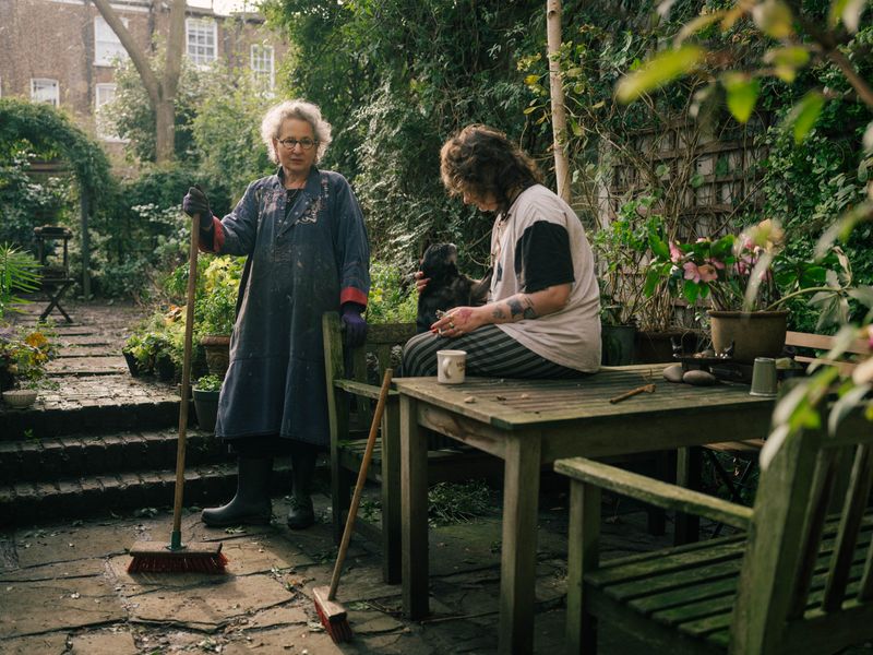 © Fotómetro - Carey gardening while Lois is having a smoke with her dog.