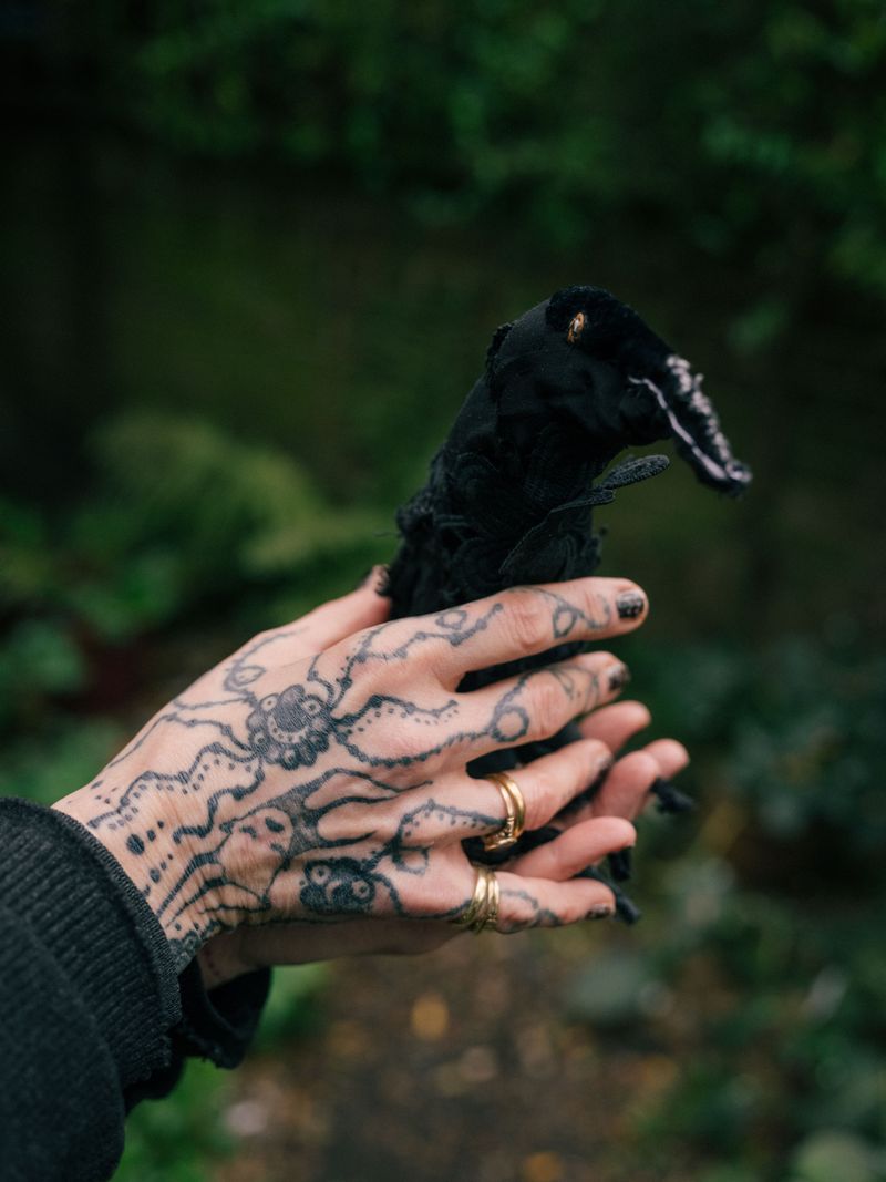 © Fotómetro - Carey holding her home made crow doll, in her garden.