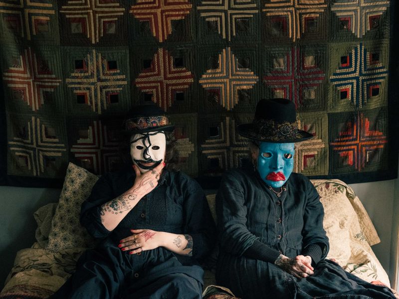 © Fotómetro - Lois and Carey, wearing their home made clay masks and hats, in Carey's bedroom.