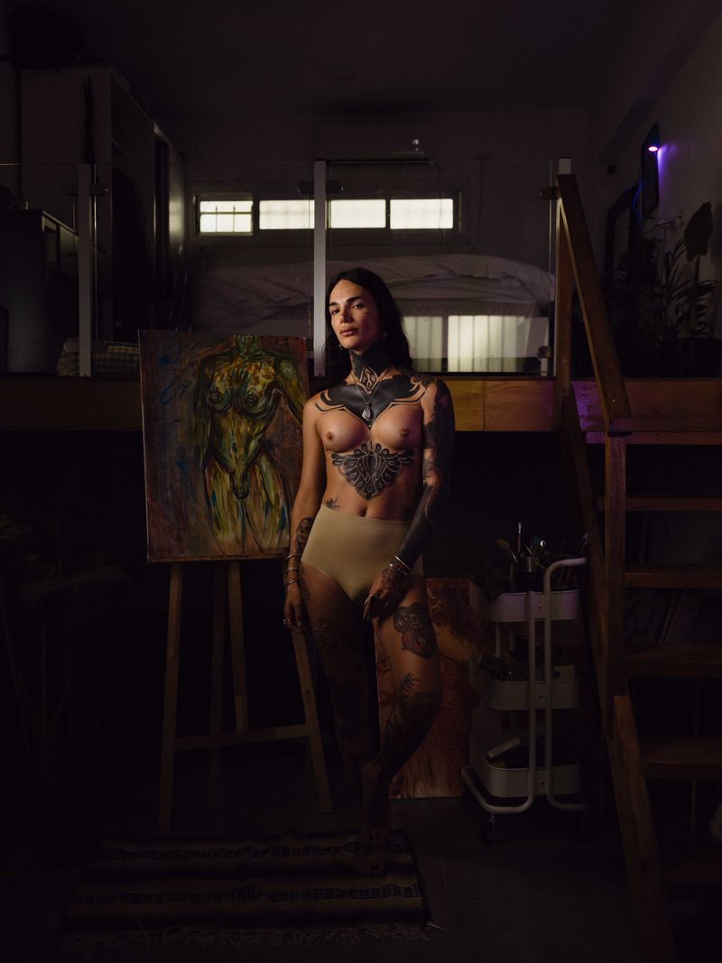 © Fotómetro - Mariel in her apartment, posing next to her self portrait painting.