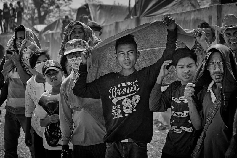 © Alain Schroeder - Indonesia, Sumbawa Island, Moyo, Onlookers, protect themselves from the sun with whatever is at hand.