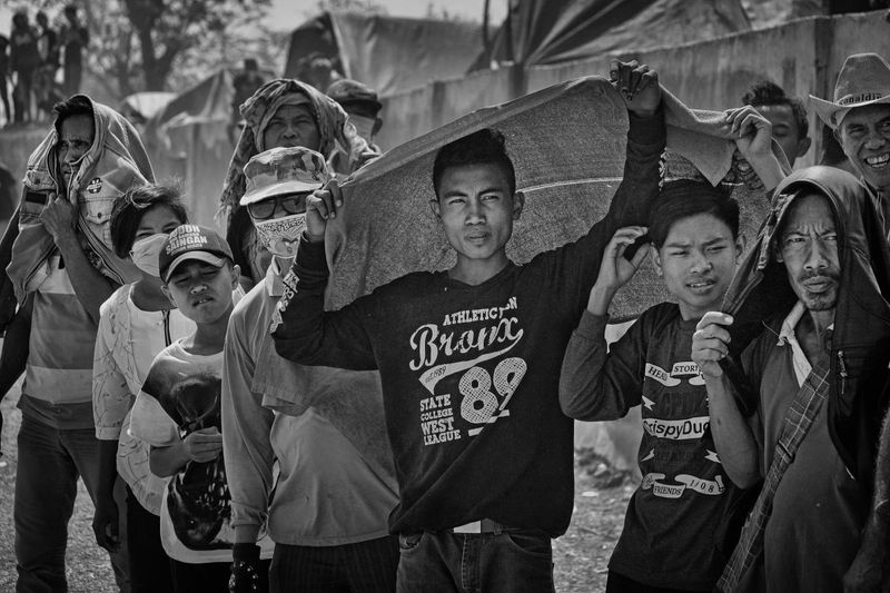 © Alain Schroeder - Indonesia, Sumbawa Island, Moyo, Onlookers, protect themselves from the sun with whatever is at hand.