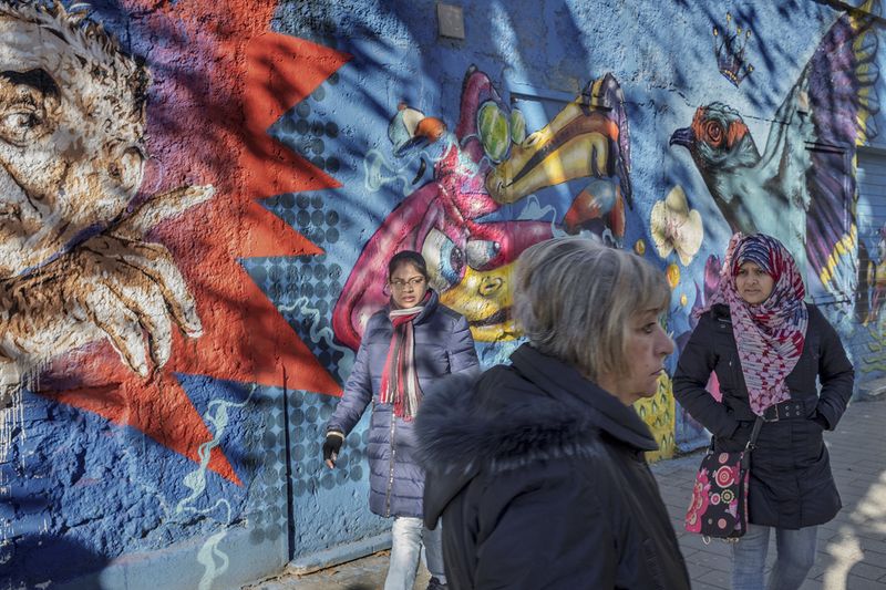 © Paolo Patrizi - A street scene bathed in winter sunlight. Women walk past a mural on Via di Torpignattara, in the eastern periphery of Rome.