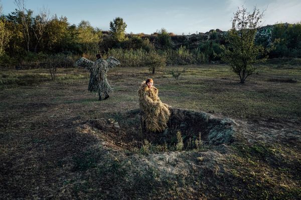 © Alena Grom - A local resident sits on a crater left by an explosion.
