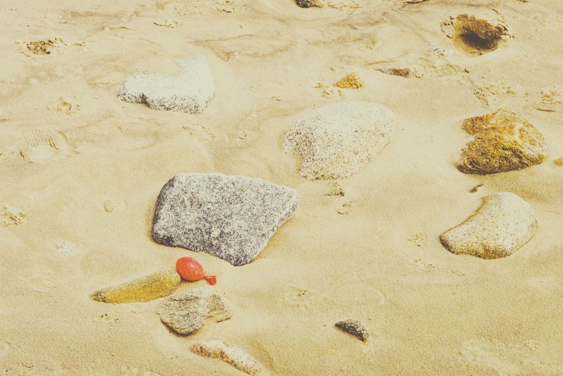 © Eduardo Rosas - A red balloon caught between rocks on the shoreline