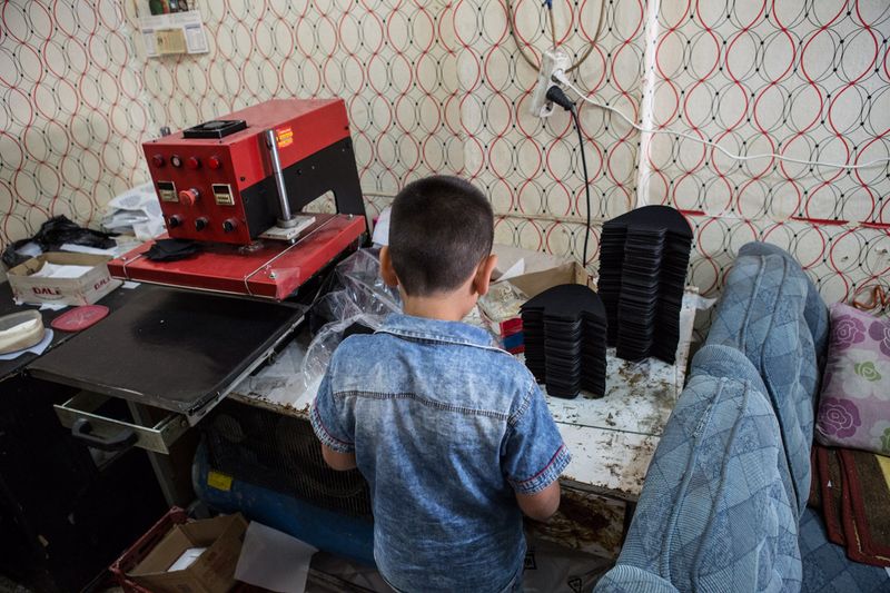 © valeriomuscella - A Syrian 9 years old boy works in a workshop where he produces decoration for shoes. Gaziantep, May 2016.
