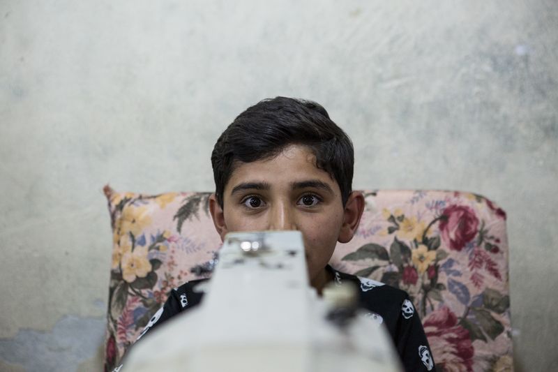 © valeriomuscella - A 12 years old Syrian boy sews 10 hours a day in a Syrian textile workshop in Gaziantep. Turkey. May 2016.