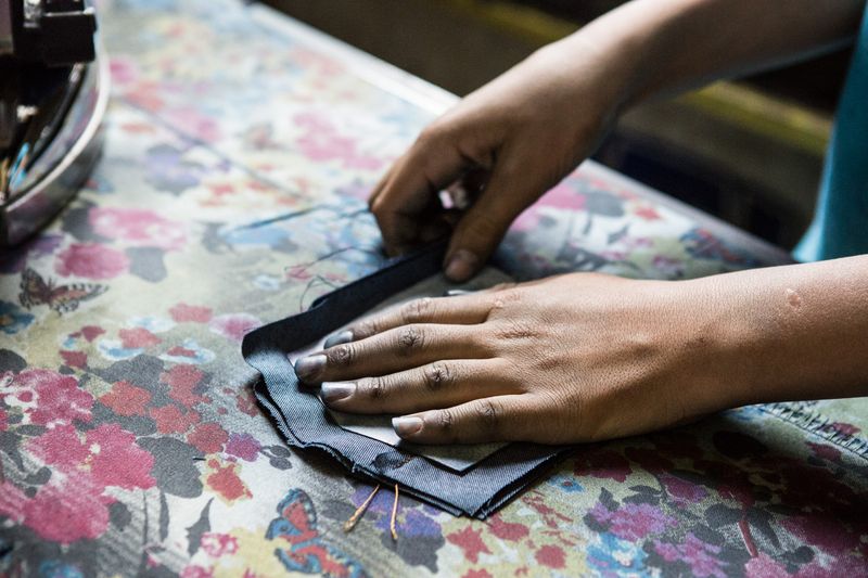 © valeriomuscella - The hands of a Syrian child are seen while ironing a pocket for jeans. Gaziantep, May 2016.