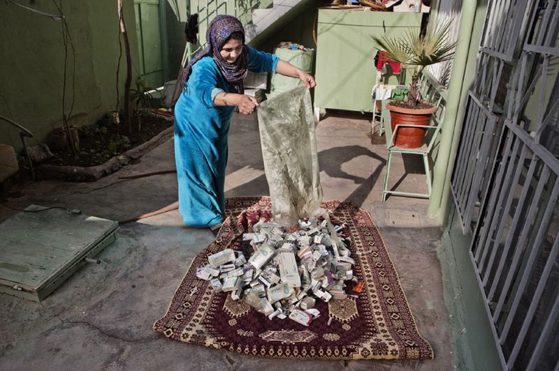 © Antonio Zambardino - The wife of Mr Ali Mahmoud Muhammad Empties their collection fo empty med-boxes on a carpet