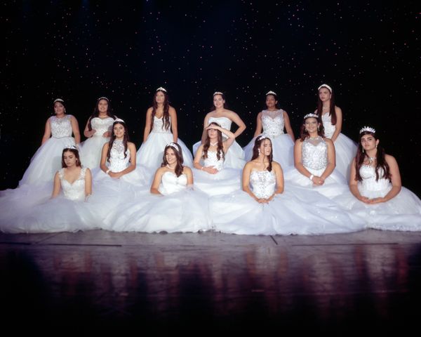 © Samantha Cabrera Friend - A group of quinceañeras in traditional dresses try their best to hold their pose.