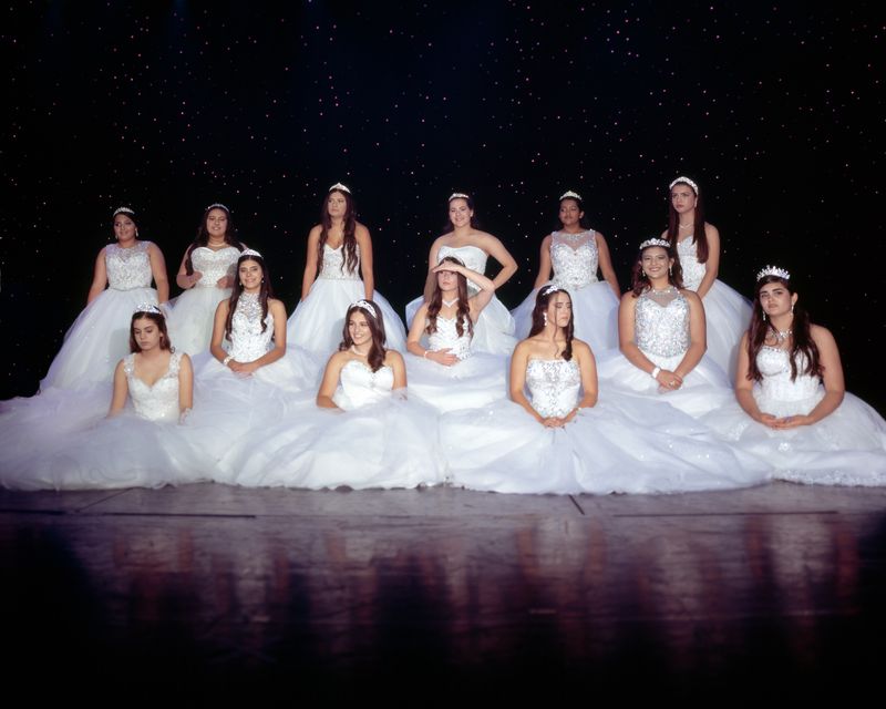 © Samantha Cabrera Friend - A group of quinceañeras in traditional dresses try their best to hold their pose.