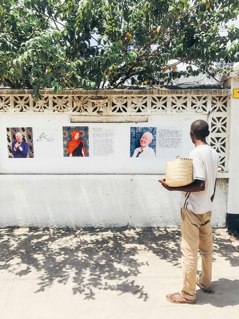 © Soraya Matos - *A Passer-by stops and approaches to read posters, and others gathered – Mikocheni, Tanzania.