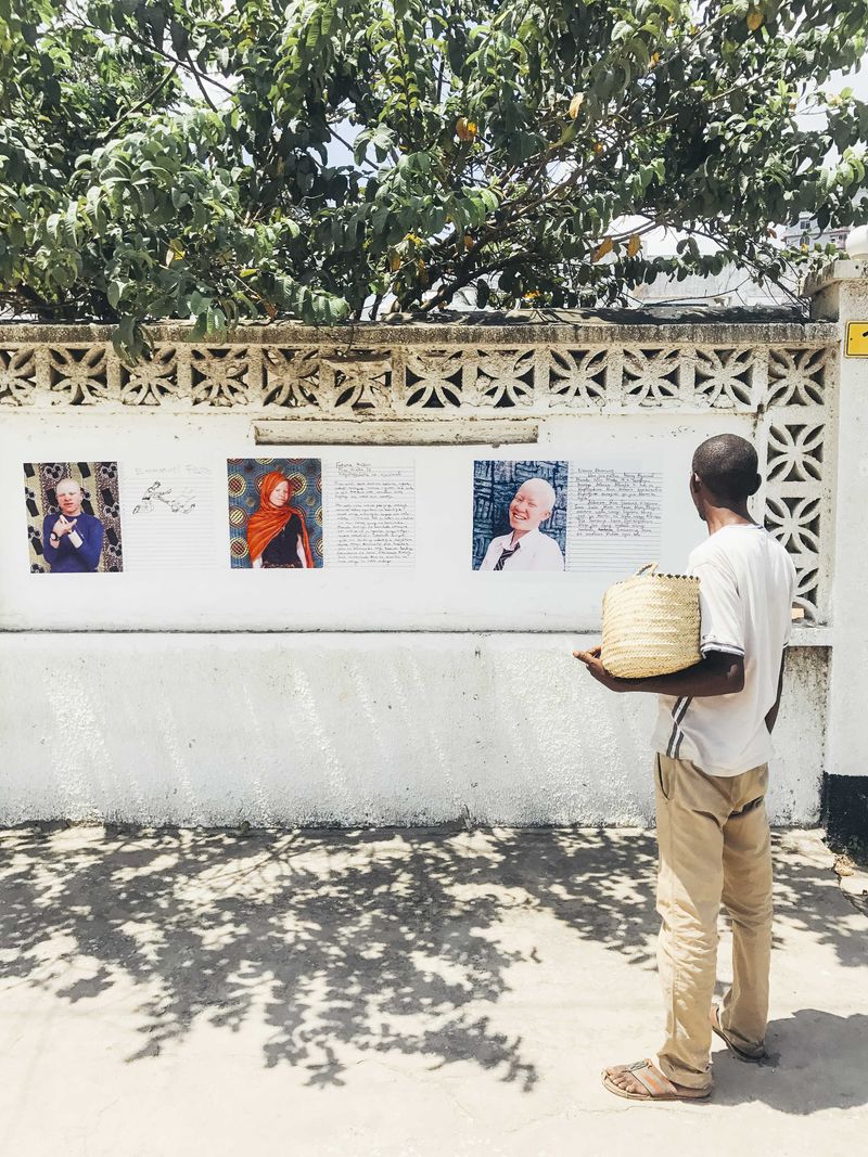 © Soraya Matos - *A Passer-by stops and approaches to read posters, and others gathered – Mikocheni, Tanzania.