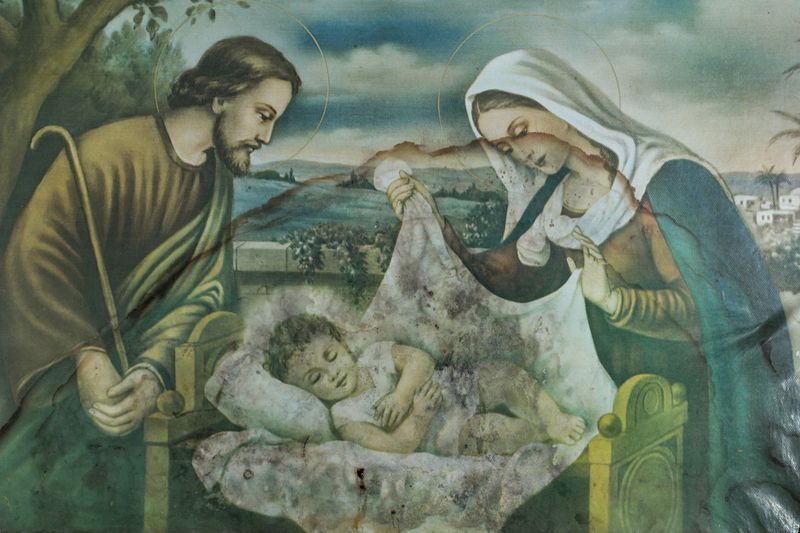 © Nicolás Bernal - A painting depicts the HolyFamily, with Joseph and Maryleaning over the infant Jesus, in an interior setting.