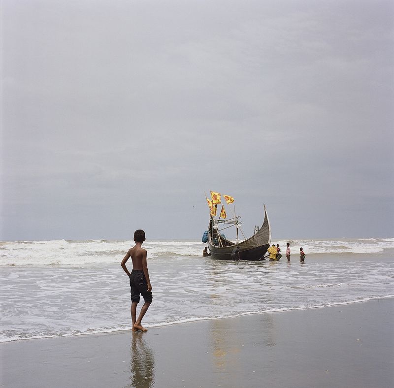 © Misty Keasler - A young fisherman watches a boat returning to the shore.