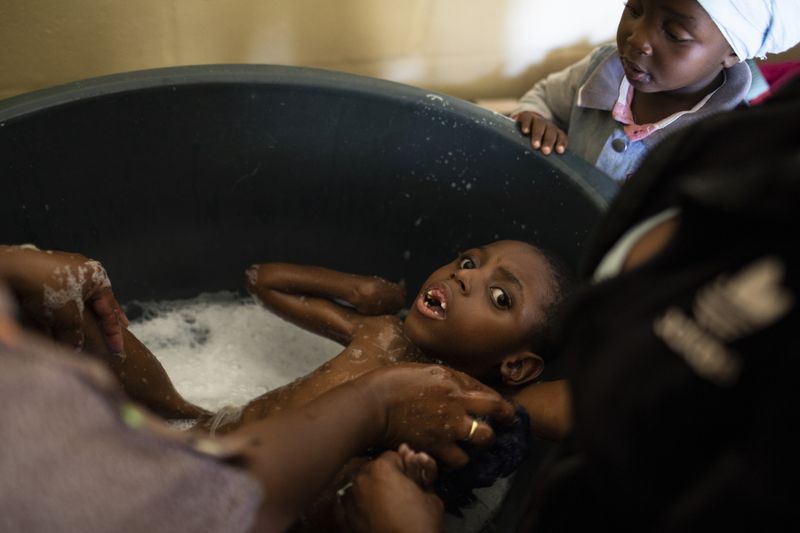 © Ilvy Njiokiktjien - Efewe (6), taking a bath with the help from his mother and grandmother in Samora Machel, a township close to Cape Town.