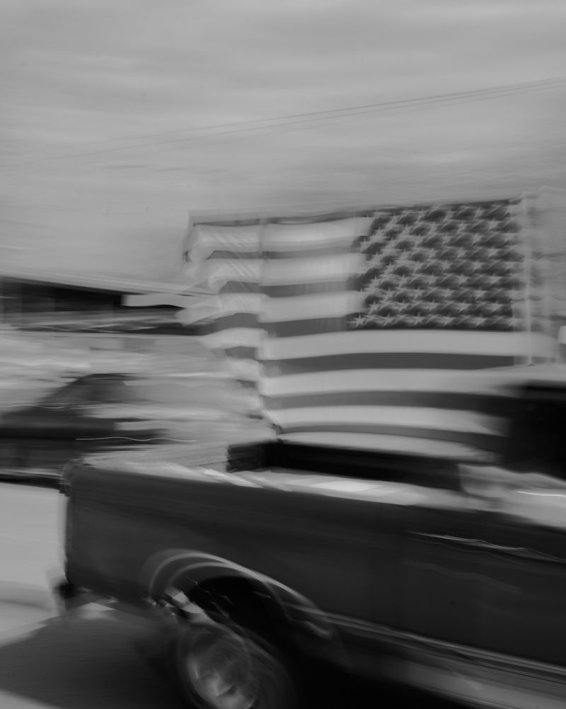 © Jordan Conway - A truck flying the American flag passes by a ranch in rural Texas hosting a Christian Nationalist rally.
