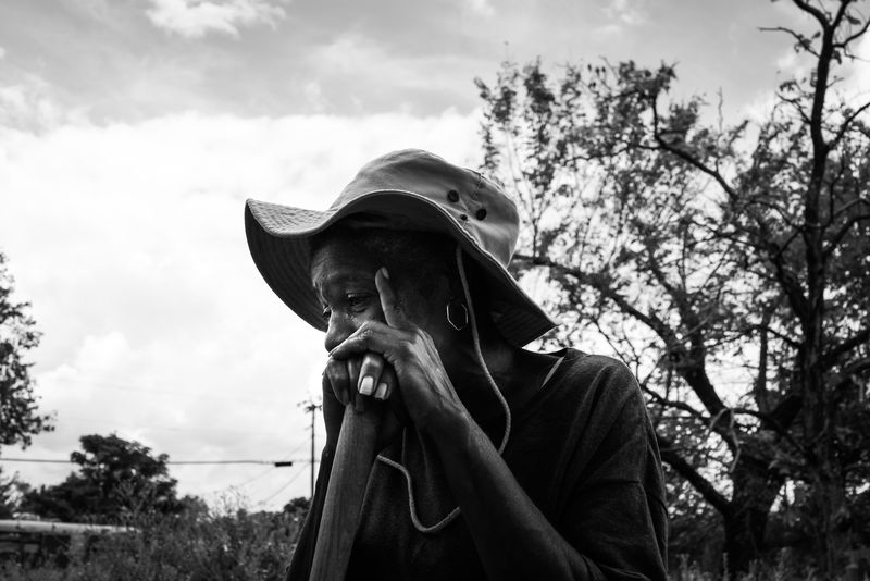 © Richard Sharum - Ms. Betty leans on a garden hoe to rest from weeding in her front yard. 2018.