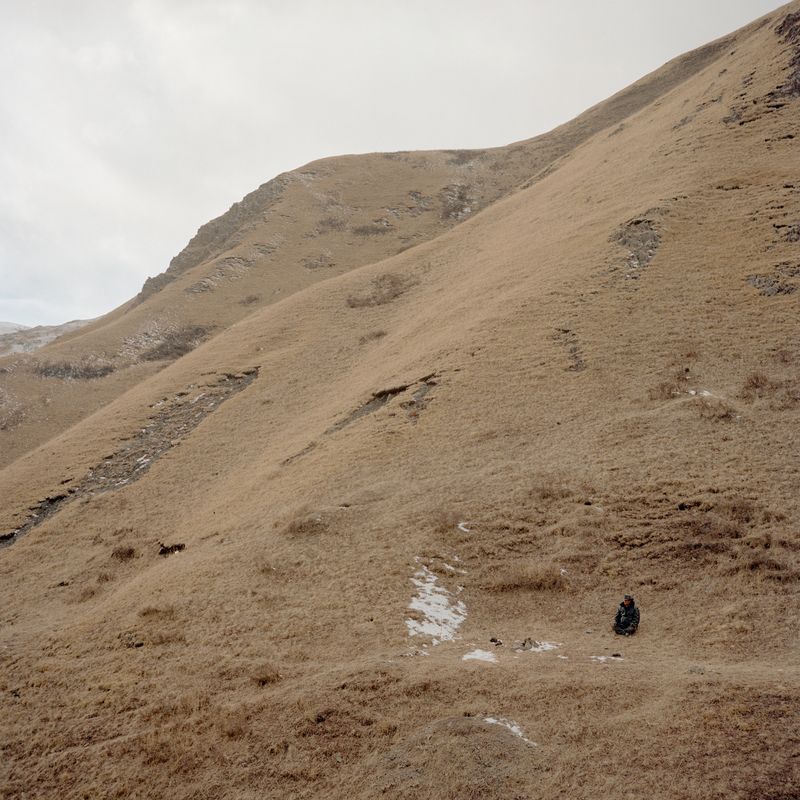 © Hao Wu - A tibetan man sits on a hill. Dari, Tibetan Autonomous Prefecture of Golog, Qinghai province, China. 2024.