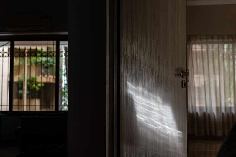 © Alisha Vasudev - A small patch of light streams in from a window, in an otherwise dimly lit house.