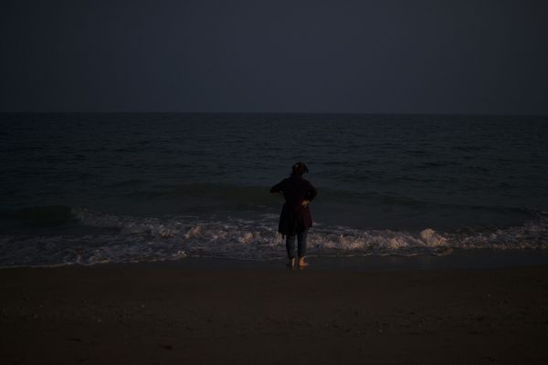 © Marjan Yazdi - A woman standing in front of a very quite beach of the Persian gulf, while uncovering her hijab.