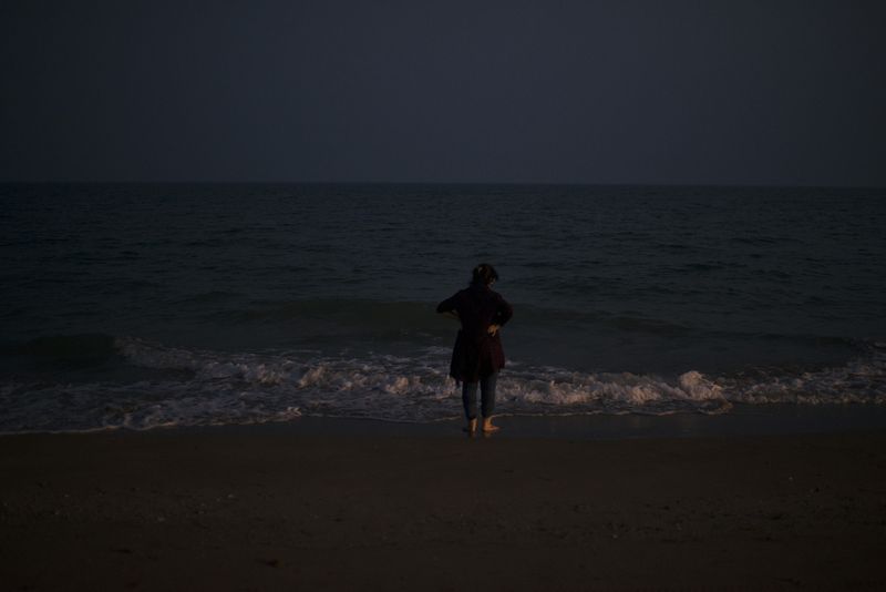 © Marjan Yazdi - A woman standing in front of a very quite beach of the Persian gulf, while uncovering her hijab.