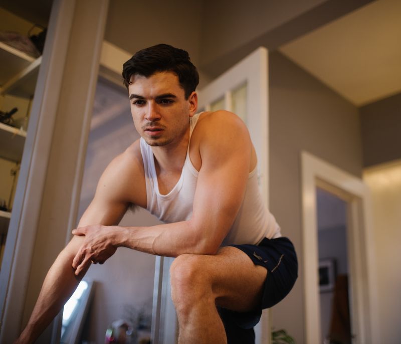 © Gili Benita - Sam (24), streching out before his work out inside the Ridgewood apartment NYC, April 21st 2020.