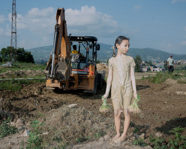 © Amit Machamasi - An excavator makes way for land plotting even as a child prepares to plant rice saplings in Bhaktapur's Sipadol, Nepal.