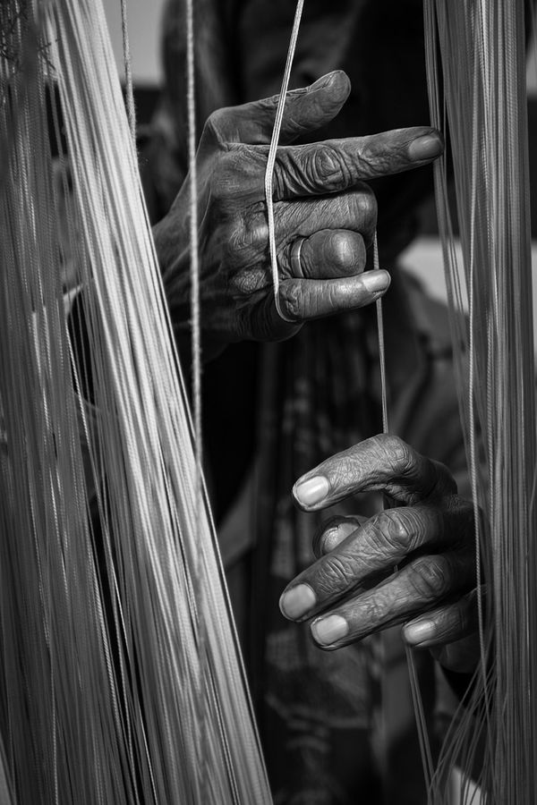 © Simone Campedelli - In the dim light of Jaipur’s looms, the hands move like memories trapped between creation and confinement.