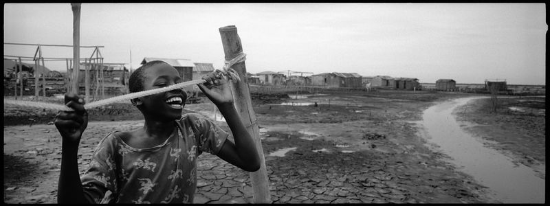 © Benjamin Rusnak - Despite the fetid swamp environment of a Cap Haitien slum, a child still finds moments of simply joy and laughter.