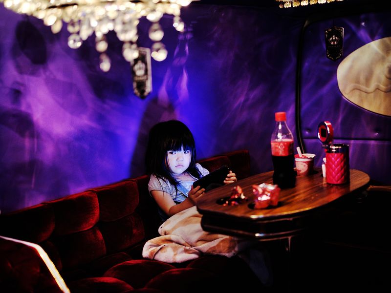 © Julie Glassberg - Little girl in the back on a dekotora, playing with a phone.