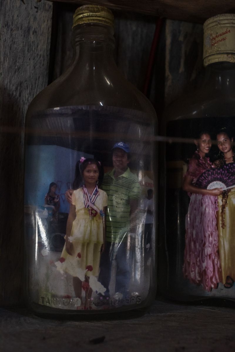 © Katherine Jack - Family photographs displayed in old rum bottles to keep off the sea air. 2018