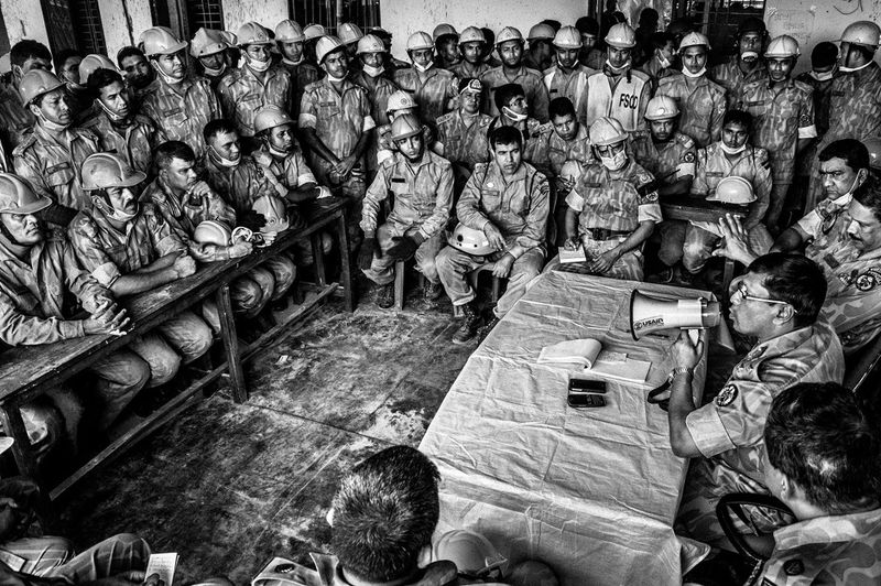 © Rahul Talukder - Rescue workers attending an official meeting besides the collapsed building.