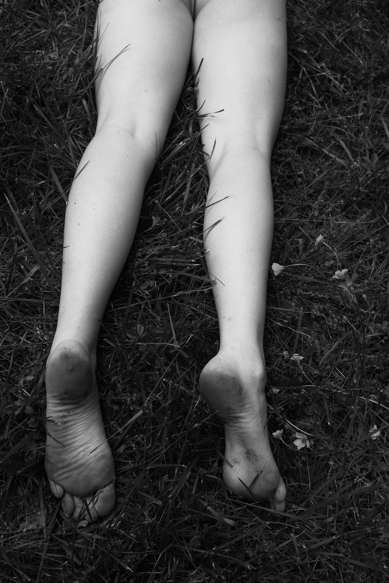 © Jillian Freyer - Sadie lays down in the long summer grass, dirty feet shining up towards the sky.