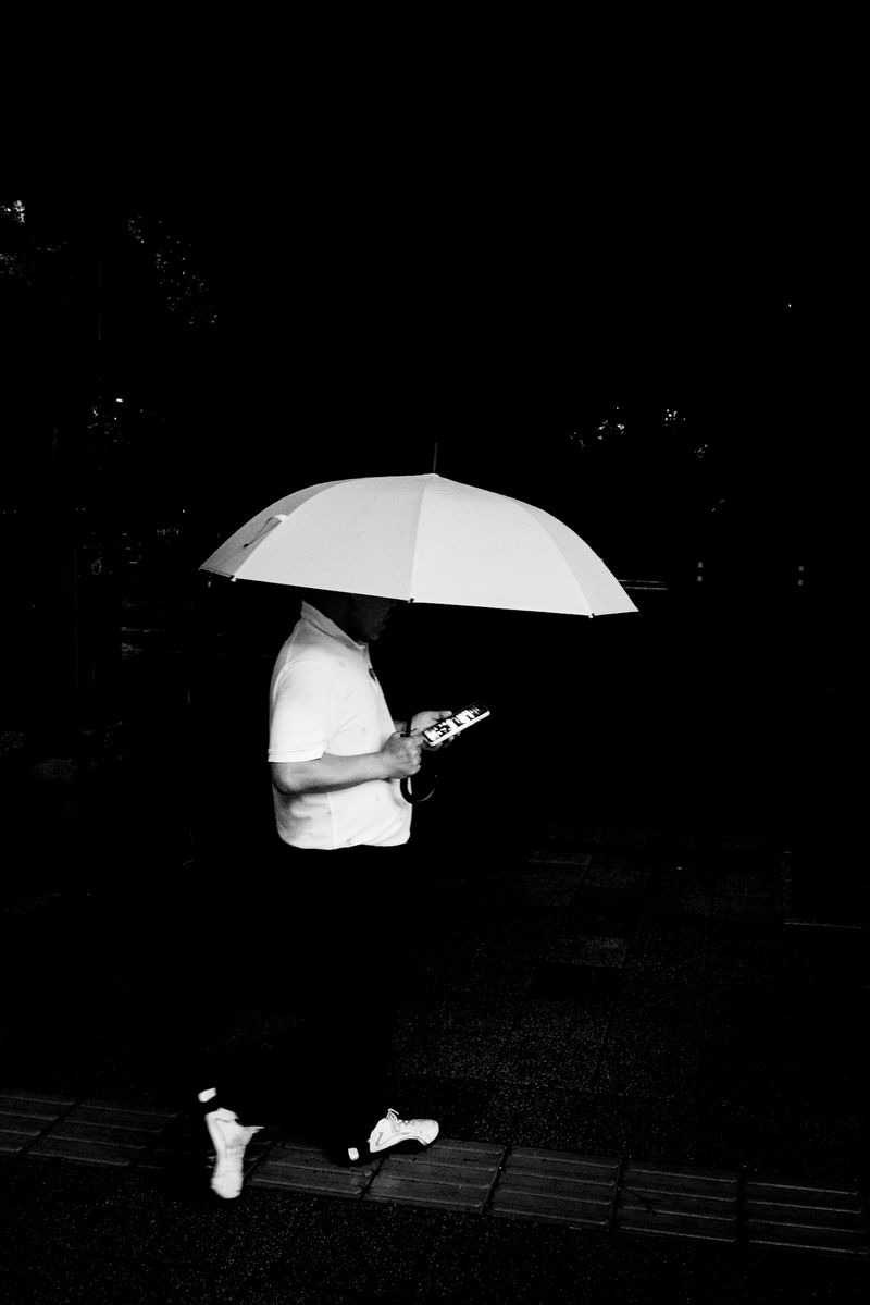 © G.S - Held Devotion.Beneath the umbrella, he walks on. As if drawn—across the hush of night.
