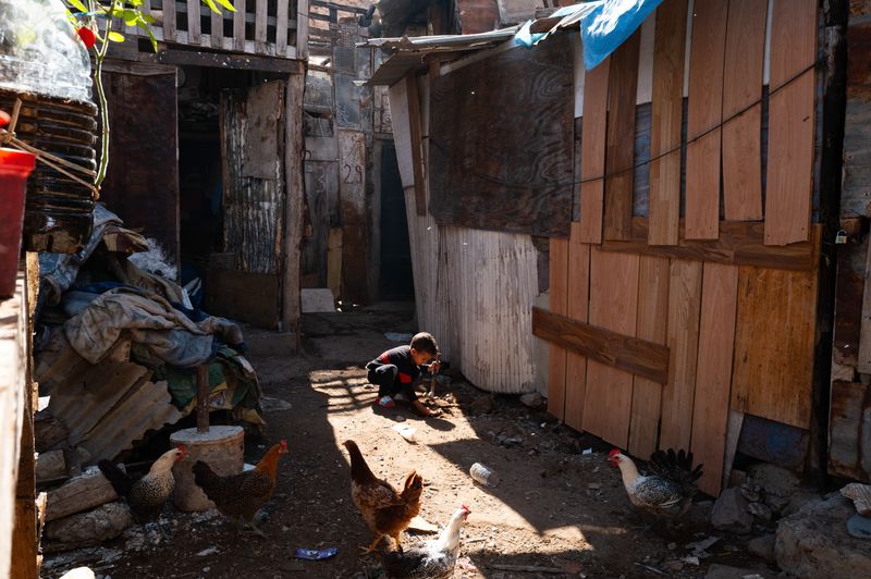 © Jacopo Da Col - A young child playing with sand in the slums, amid garbage and animals.