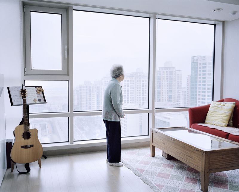 © Giulio Di Sturco - An old Lady looking outside her window on her new home in New Songdo city.