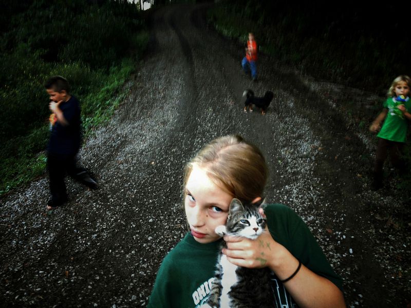 © Maddie Mcgarvey - Sonya holds her neighbor's cat next to her grandmother's home.