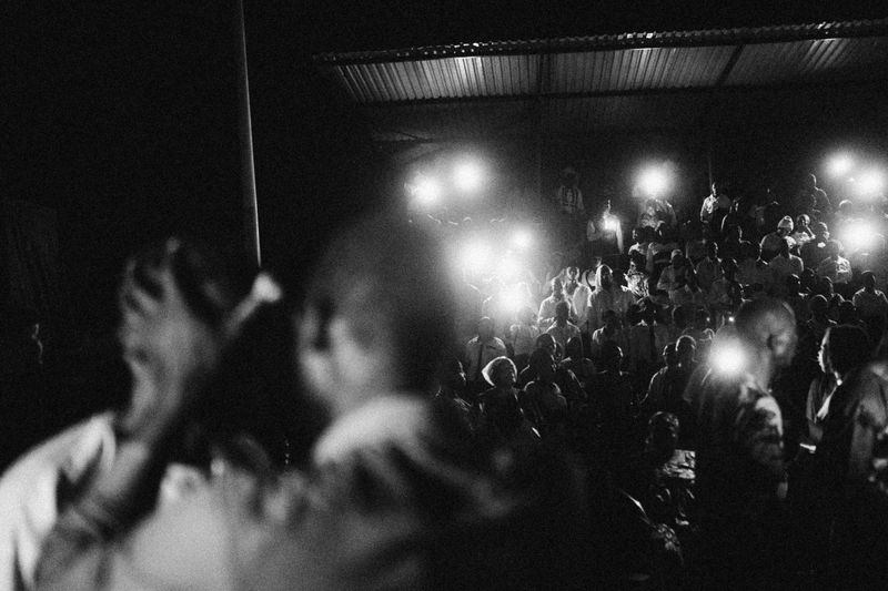 © Jeff Tidwell - A pastor prays for a young man during an electrical outage, lit by mobile phone lights at the nightly meetings