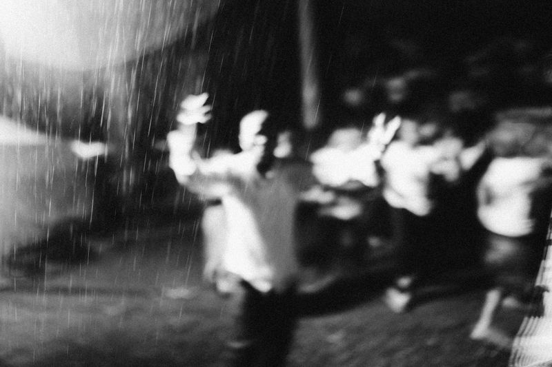 © Jeff Tidwell - A  pastor holds up his hands in worship among a group of young adults running and shouting during a rainstorm